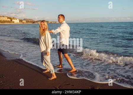 Full-length photo of happy couple walking along the beach Stock Photo