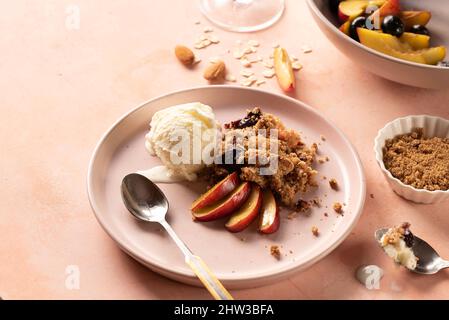 Gluten free peach crumble with fresh peach almond four, oats and topped with Ice-cream for breakfast or dessert Stock Photo