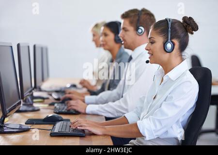 How can we help. Shot of a client services team fielding phonecalls. Stock Photo