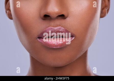 Lucious lips. Cropped shot of a young womans mouth against a purple background. Stock Photo