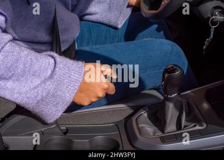 Closeup of young woman pulling handbrake lever in car Stock Photo