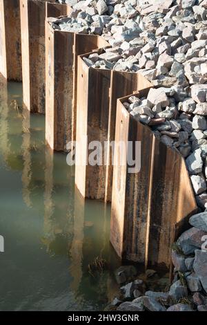 Sheet metal, piling, position, located in ground, supporting, river banks, interlocking edges, driven into ground, earth retention excavation support. Stock Photo
