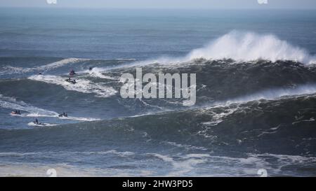 Jet skis in Praia do Norte positioning themselves on a big waves day. Nazaré, Portugal. Stock Photo