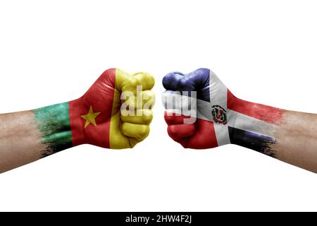 Two hands punch to each others on white background. Country flags painted fists, conflict crisis concept between cameroon and dominican republic Stock Photo