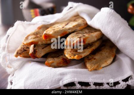 Homemade Tlacoyos. Mexican pre hispanic dish made of corn flour patty filled with chicharron prensado (pressed pork rinds). Popular street food in Mex Stock Photo