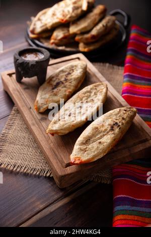 Tlacoyos. Mexican pre hispanic dish made of corn flour patty filled with chicharron prensado (pressed pork rinds). Popular street food in Mexico. Stock Photo
