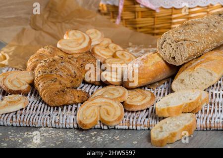 Wheat and grain baguettes, croissants and biscuits on wicker mat Stock Photo