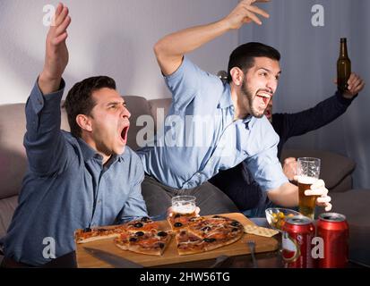 Males watching tv at home and having fun Stock Photo