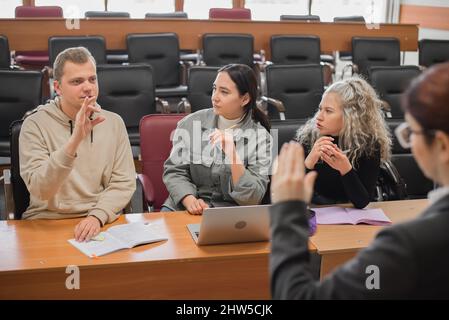The teacher and students communicate in sign language in the classroom. Hearing impaired and deaf people Stock Photo
