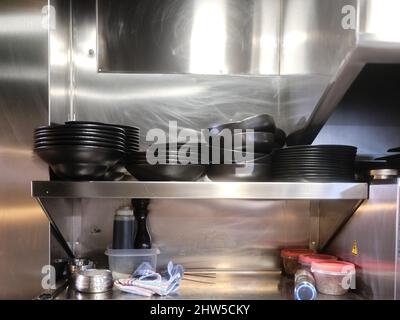 Restaurant with metal shelving with stacked dishes ready for kitchen service Stock Photo