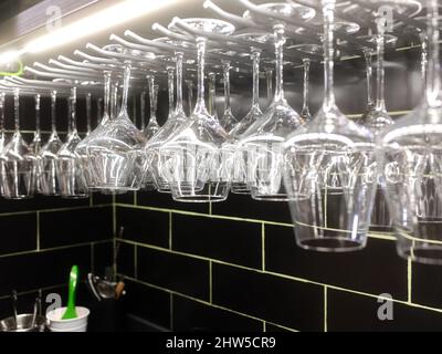 Wine glasses hanging from a rack in a restaurant Stock Photo