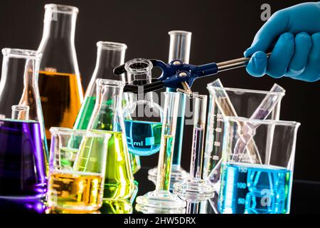 Chemist combining colorful liquids in laboratory glassware Stock Photo