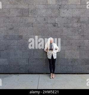 Portrait of senior woman leaning against wall Stock Photo