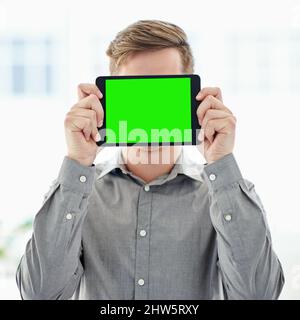 Youve got to see this. Shot of a man holding a digital tablet with a chroma key screen in front of his face. Stock Photo