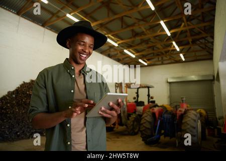 Mixed race male farmer typing on digital tablet standing in shed Stock Photo