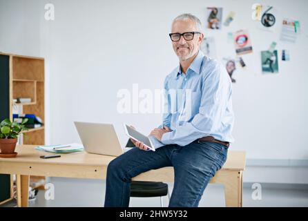 Portrait of a handsome businessman working on a digital tablet. The commercial designs displayed in this image represent a simulation of a real Stock Photo