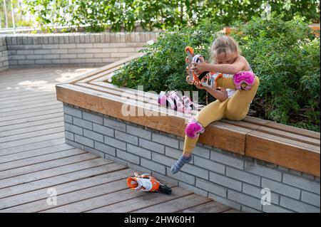 Little girl learns to roller skate outdoors. Stock Photo