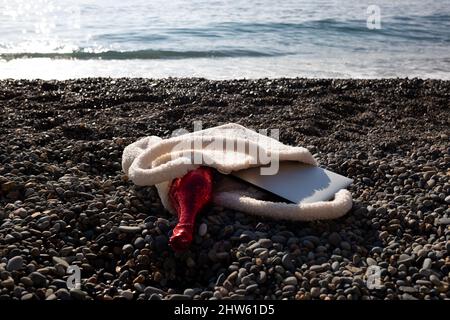 a bag with a laptop and a bottle of champagne lies on the coast of the sea Stock Photo