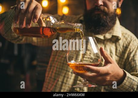 Man with glass brandy or cognac. Man holding a glass of whisky. Portrait of man with glass of whiskey isolated on black studio. Stock Photo