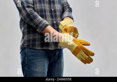 man or builder putting protective gloves on Stock Photo