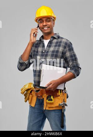 indian builder in helmet calling on smartphone Stock Photo