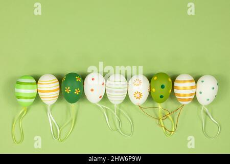 A row of painted multi-colored eggs in a row on a green background. View from above. Place for inscription text. Stock Photo