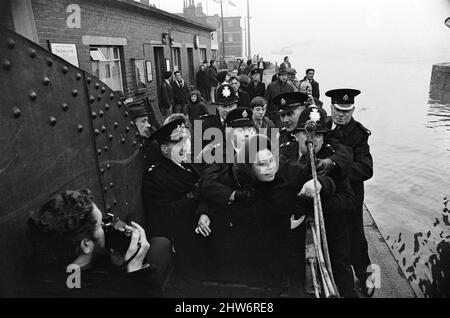 Police hold back Mrs Lillian Bilocca on the quayside at Hull. She is held back as the 717-ton St Keverne nosed out of St Andrew's Dock, Hull, the port from which two trawlers and 40 men are missing. She had threatened to leap aboard any trawlers putting to sea under-manned or not carrying a radio operator. Lillian Bilocca was a fisheries worker and campaigner for improved safety in fishing fleet as leader of the 'headscarf revolutionaries'. Circa February 1968. Stock Photo