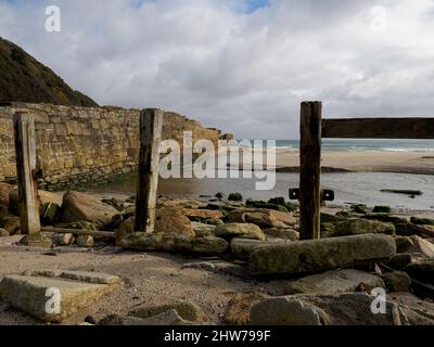 The remains of the pier wall part of the entrance to the harbour, Pentewan, Cornwall, UK Stock Photo
