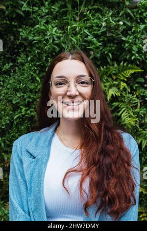 Portrait of smiling woman with long red hair pulling hand towards camera. Beauty portrait of natural woman having fun Stock Photo