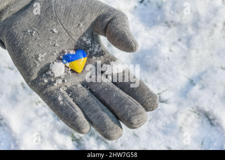 Yellow and blue small heart in a hand with glove, colors of the Ukraine flag, symbol of preserving the country from the crisis of the Russian invasion Stock Photo