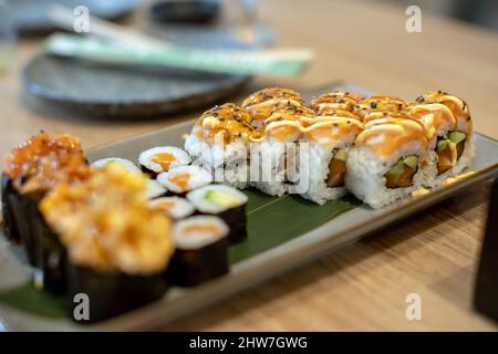 Plate with sushi and noodles on a table in a restaurant, dinnertime Stock Photo