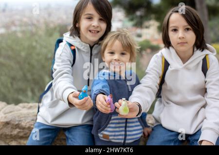 Children, cute boys, playing with ceramic clay whistle in the form of bird, souvenir from park Guell in Barcelona, Spain Stock Photo