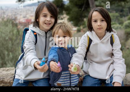 Children, cute boys, playing with ceramic clay whistle in the form of bird, souvenir from park Guell in Barcelona, Spain Stock Photo