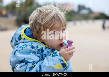 Child, cute boy, playing with ceramic clay whistle in the form of bird, souvenir from park Guell in Barcelona, Spain Stock Photo