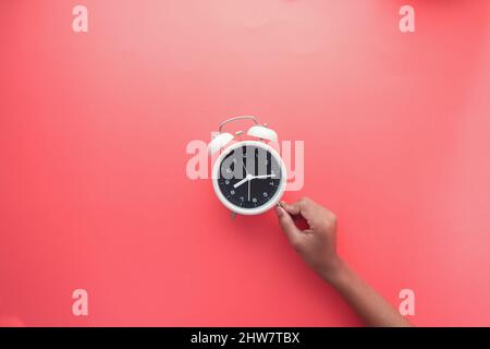 holding a old alarm clock on red background. Stock Photo