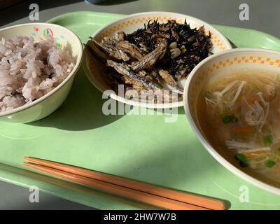 Japanese school lunch on a green plastic tray. Rice, soup and fried anchovies Stock Photo
