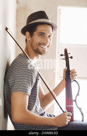 Ready to make some music. Handsome young musician holding his violin on a stairwell. Stock Photo