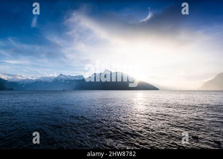 Landscape a mountain lake in the Alps. Switzerland. Sun rays over the mountain peaks. Stock Photo