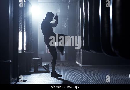 True warriors are instinctively fierce. Shot of a sporty young man kickboxing in a gym. Stock Photo