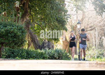 Young couple doing sports at the park. They are running and smiling Stock Photo