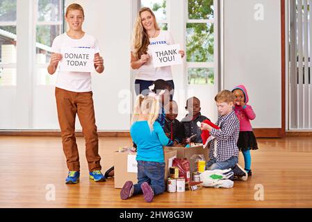 Giving back to the community. Shot of volunteers working with little children. Stock Photo