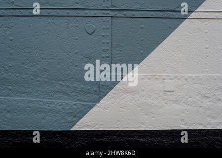metal sheets riveted together and painted grey, white and black. Part of a ships hull. Stock Photo