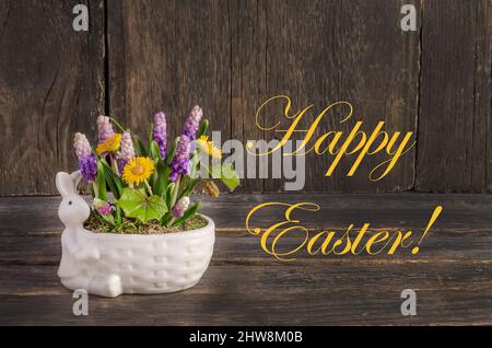 Easter card, composition with rabbit and spring flowers on a wooden background with the inscription Happy Easter Stock Photo