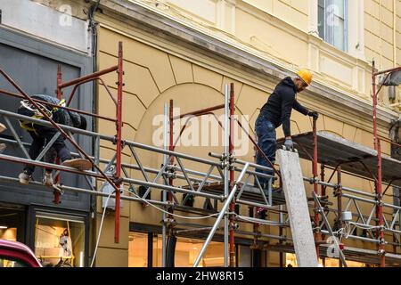 Two construction workers on a scaffold on the facade of a building during a renovation in the old town of Sanremo, Imperia, Liguria, Italy Stock Photo