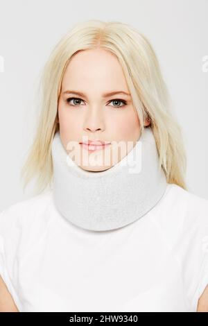 On the road to recovery. A beautiful young woman in a neck brace against a white background. Stock Photo