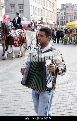 Close up of a cigarette smoking accordion player entertaining shoppers and tourists in Krakow Old Town square, Poland on market day Stock Photo