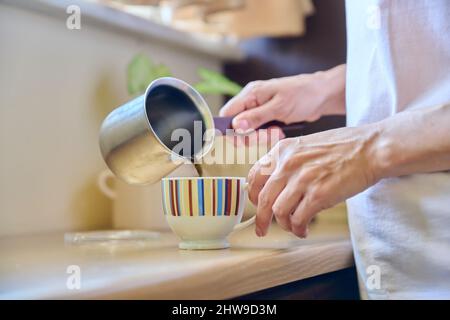 Close-up of a woman's hands preparing coffee in an iron cezve. Stock Photo