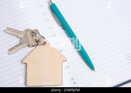 Keychain shape house with keys and ballpoint pen on an open notebook Stock Photo
