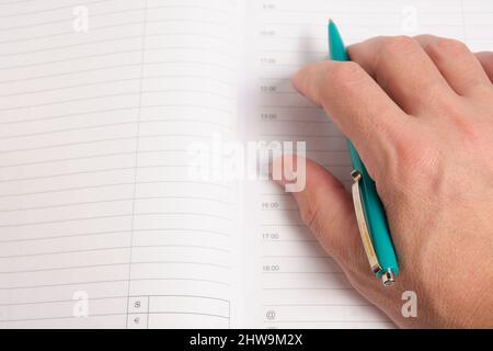 Hand with green ballpoint pen on background notepad sheets Stock Photo