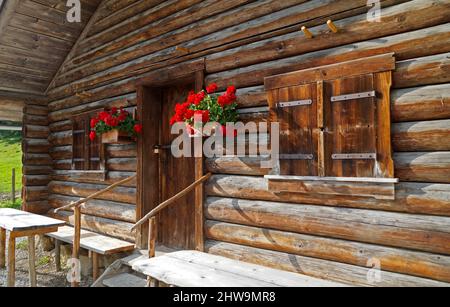 a rustic wooden cabin with geraniums on the windowsill in the German Alps (Fuessen region, Bavaria, Germany) Stock Photo